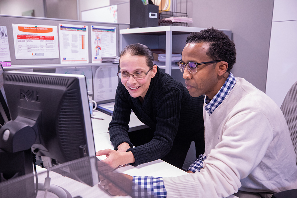 Researchers working on a project in front of a computer monitor