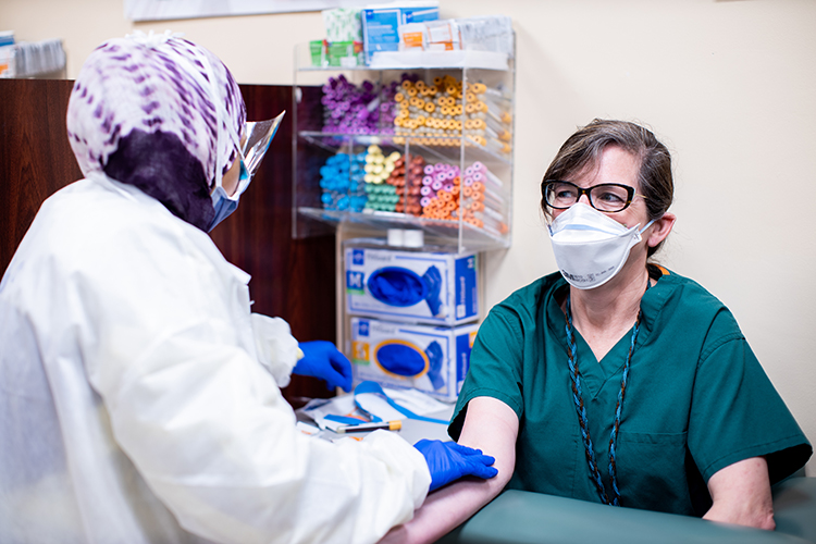 Woman wearing green scrubs prepare to get a COVID-19 anti-body test at UHealth