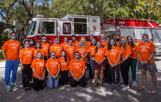 Firefighters pose for a image with a cancer researcher during a press conference